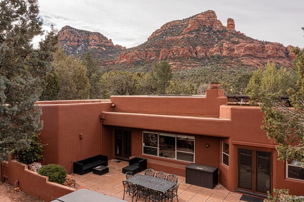 Un bâtiment moderne doté d’un patio aménagé avec du mobilier d’extérieur et offrant une vue sur des formations rocheuses rouges.