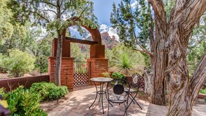 An outdoor patio with a brick pathway, a wooden pergola, and two metal tables with chairs. - Discover luxury at Sedona Hidden Dream, a spacious 4BR retreat with stunning red rock views. (Sedona)