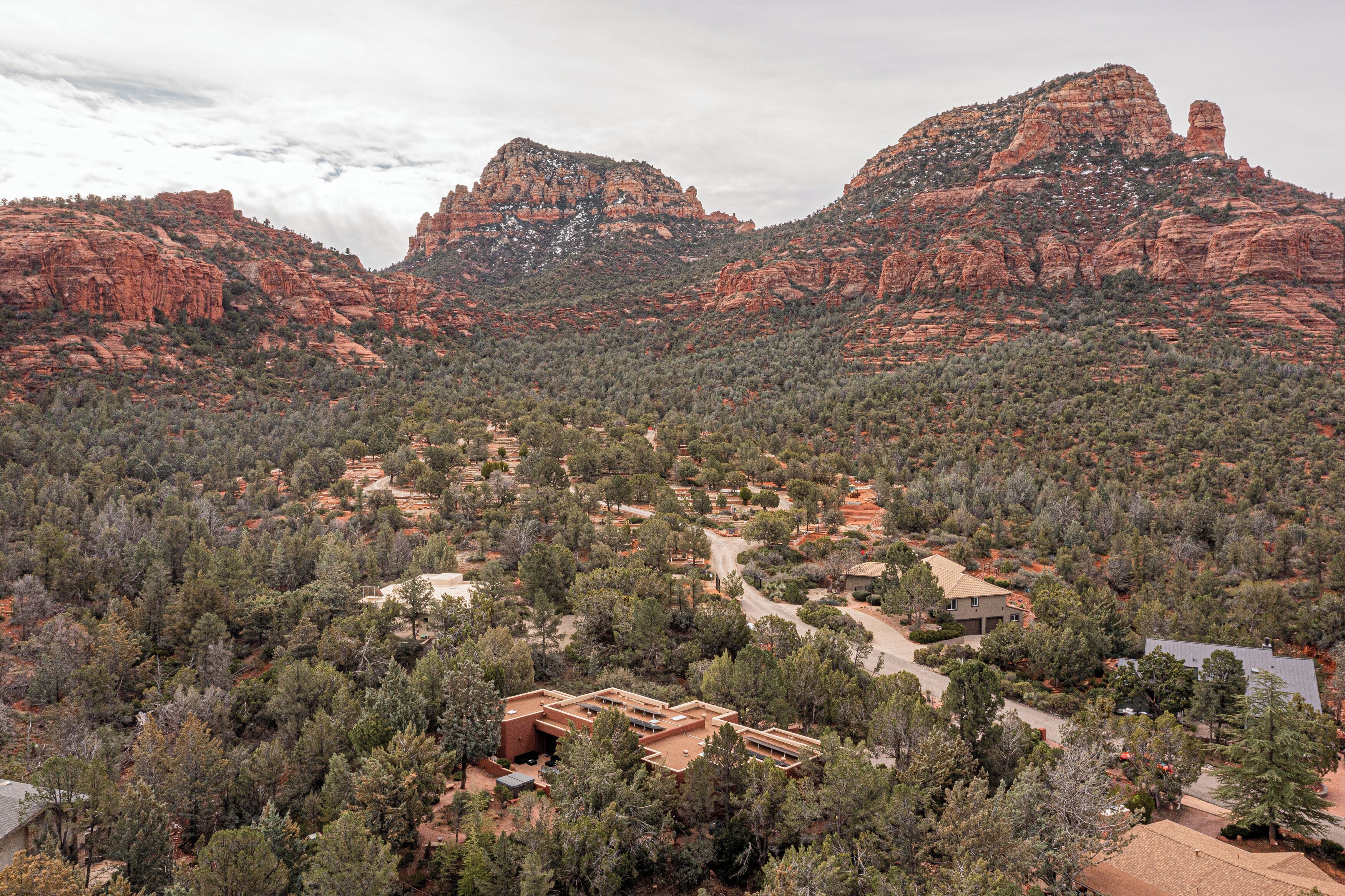 A mountainous landscape with a residential area featuring houses surrounded by dense forest.