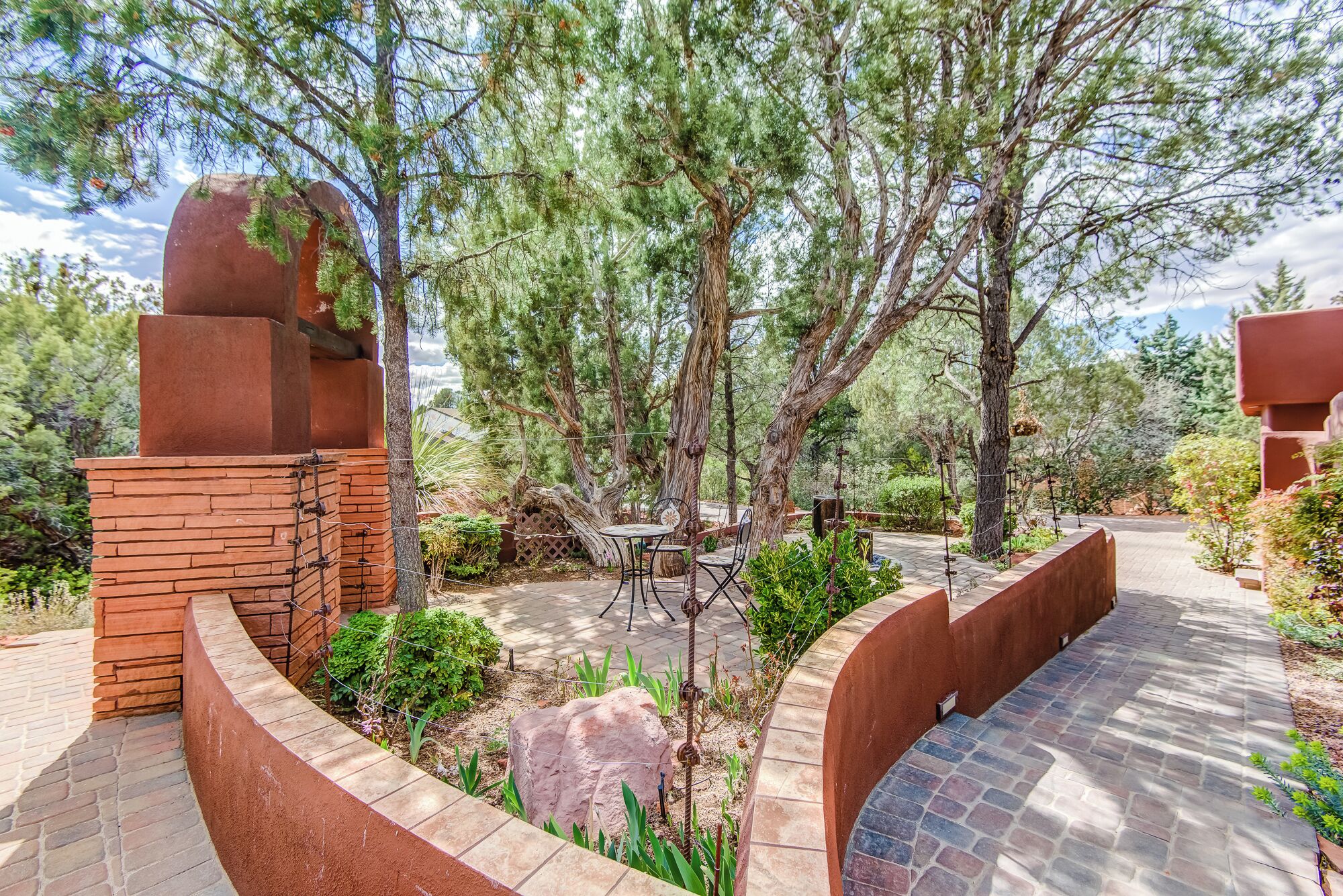 Un espace extérieur aménagé en terrasse, avec une cheminée en briques, une table entourée de chaises et un chemin en pierre.