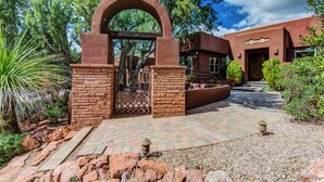 A rustic building entrance with a brick archway, a paved pathway, and surrounding greenery. - Discover luxury at Sedona Hidden Dream, a spacious 4BR retreat with stunning red rock views. (Sedona)