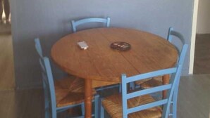 A round wooden table with four blue chairs, a decorative wall with a wave pattern, and a star ornament.