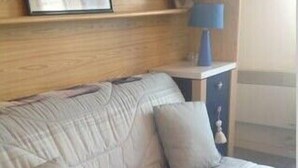 A sofa with a floral pattern, a lamp on a side table, and a framed picture on the wall.