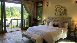 Ein Schlafzimmer mit einem großen Bett, Seeblick und einer Holzterrasse.