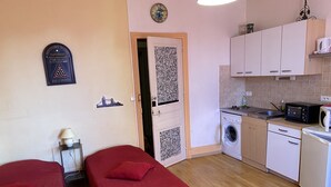 A compact room with two single beds, a washing machine, a microwave, and a small kitchenette. - Large studio located opposite the spa park. (Vittel)