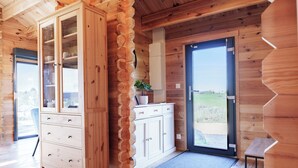 L’intérieur d’une cabane en bois, avec un meuble en bois, une plante et une porte donnant sur l’extérieur.
