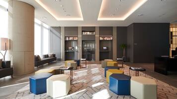 A modern lobby with seating areas, a reception desk, and a bookshelf.