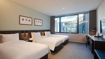 A hotel room with two beds, a desk, and a large window offering a city view.