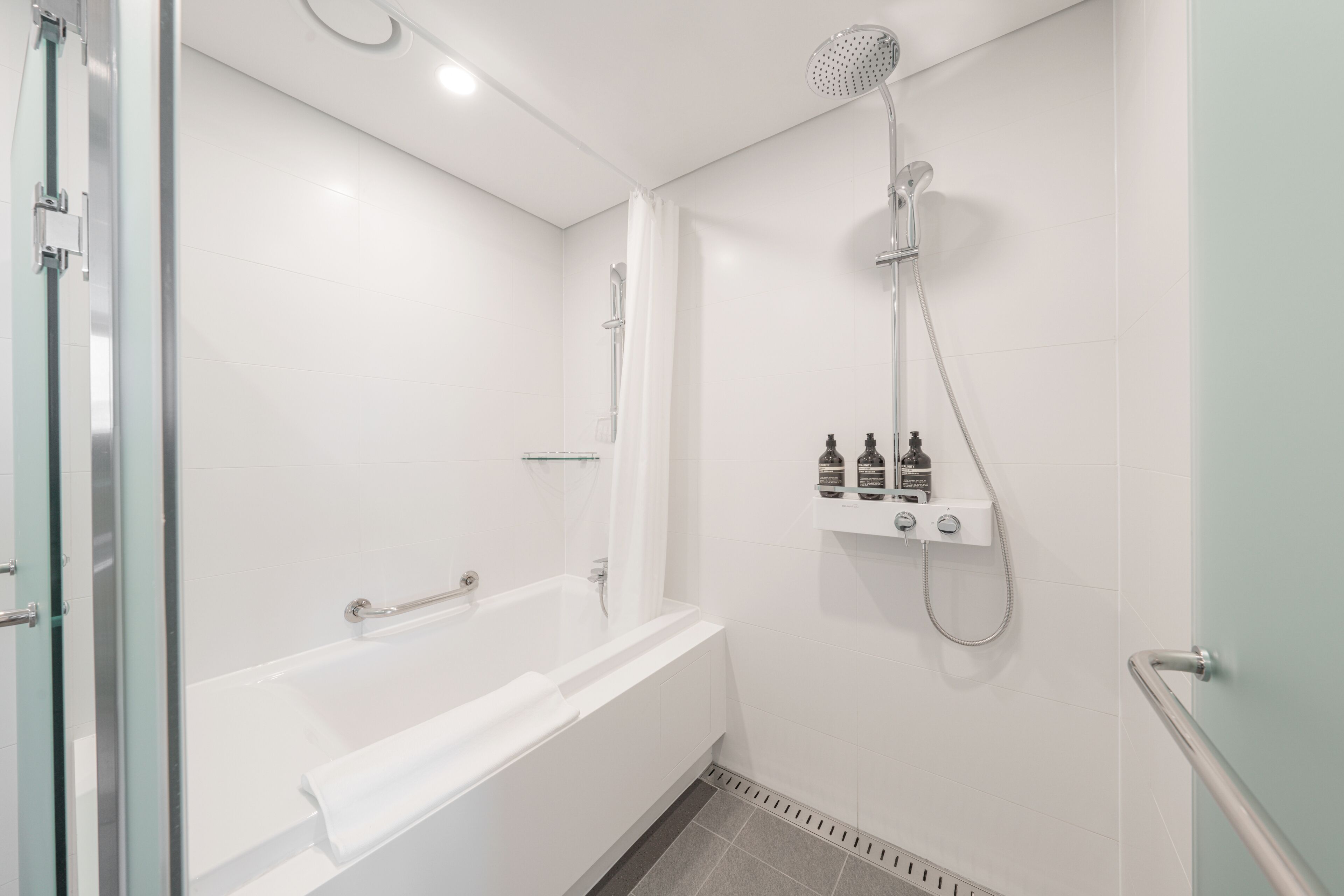Une salle de bain moderne avec une baignoire, une douche et un espace de douche séparé par des parois en verre.