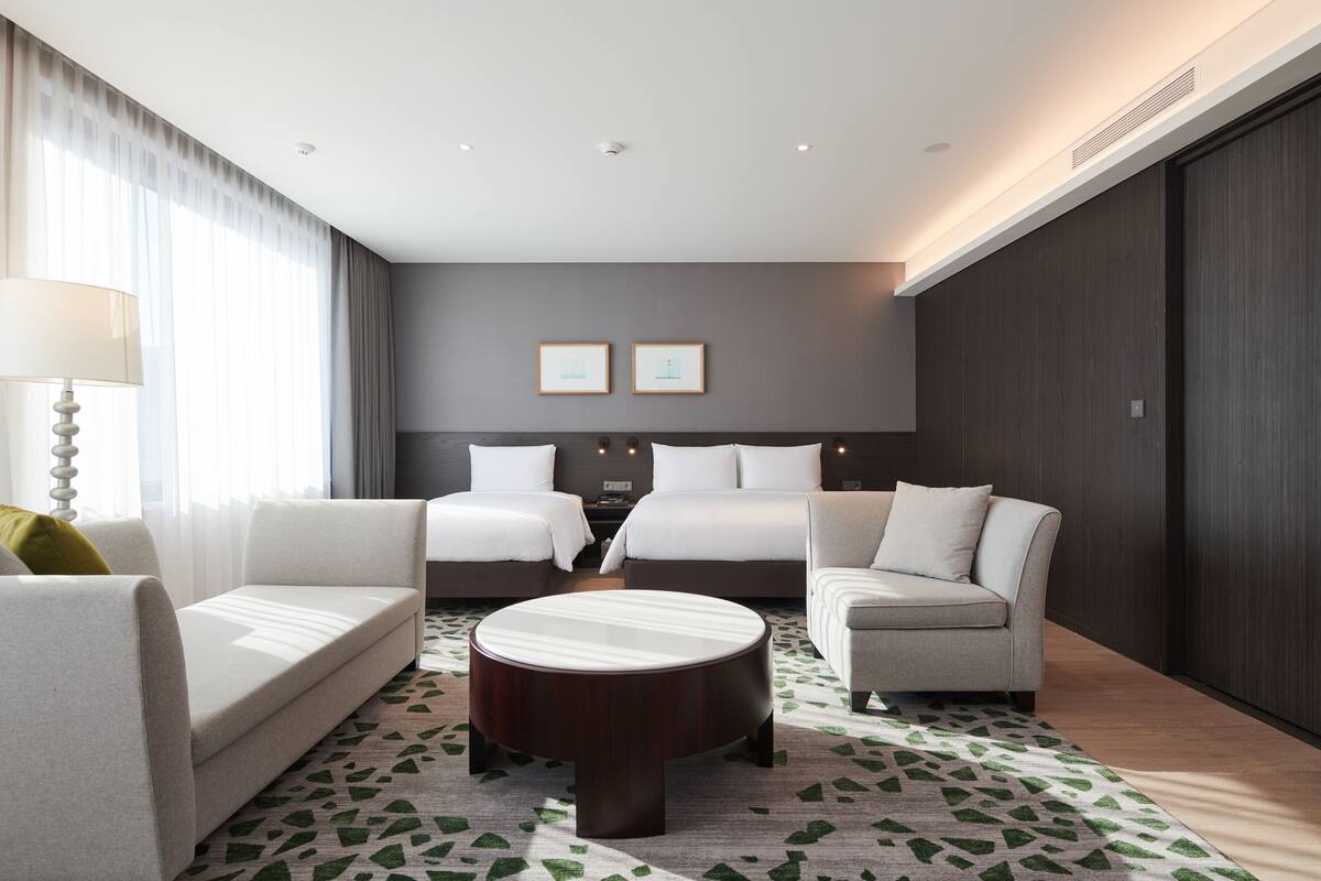 Ein Hotelzimmer mit einem Bett, zwei Sofas, einem Couchtisch und einem gemusterten Teppich.