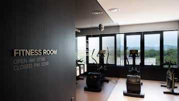 Una sala de fitness amb equip per a exercicis cardiovasculars, grans finestres i vistes cap a l'exterior.
