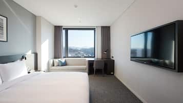 Una habitación de hotel moderna con una cama grande, un escritorio, una silla y un televisor.