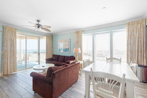 Relax in this inviting living area with a sofa, dining table, and ceiling fan, offering a view of the outdoors.