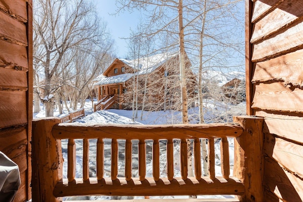 A wooden cabin with a snow-covered roof and a wooden bench in the foreground. - New! Exquisite Log Cabin home-HOT TUB, FIREPLACE, AC, Garage, walk to SKI lift (Park City)