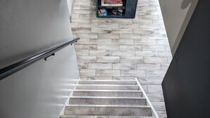 A staircase with wooden steps and a metal handrail, leading to a wall with a mounted shelf holding books. - Northern Paradise on Lake Vermilion - Year Round Home (Tower)