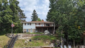 A two-story house with a stone foundation and a covered patio area. - Northern Paradise on Lake Vermilion - Year Round Home (Tower)