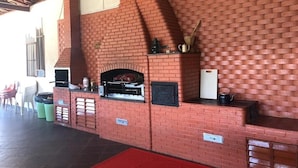 Een bakoven met schoorsteen, een plank met waterkoker en een prullenbak.