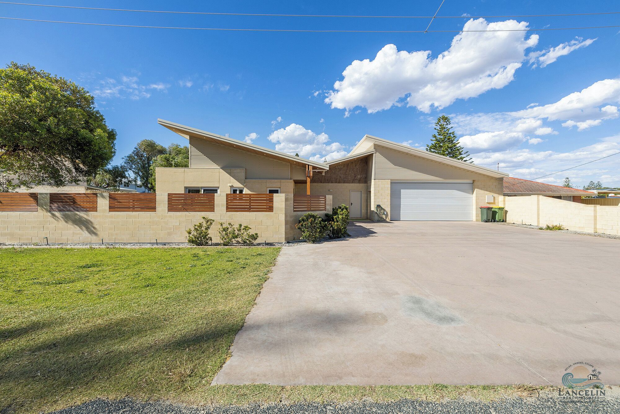 A modern two-story house with a garage, a well-maintained lawn, and a clear blue sky.