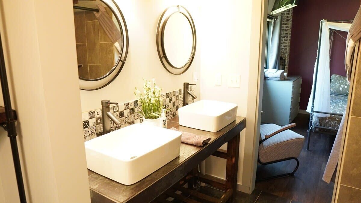 A bathroom with two sinks, a mirror, and a shower.