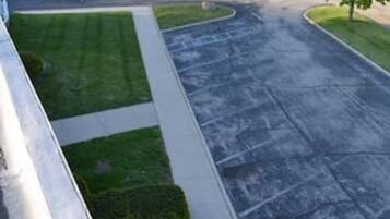 A parking lot with a paved walkway, green lawns, and trees.