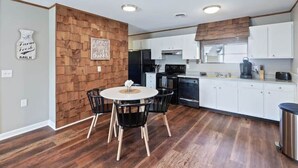 A modern kitchen with white cabinets, a central island, and a dining area with a round table and chairs. - Pawnee Duplex in Chattanooga, Unit 1 (Chattanooga)