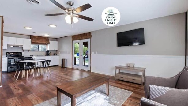 A spacious living area with a wooden dining table, a sofa, and a TV mounted on the wall. - Pawnee Duplex in Chattanooga, Unit 1 (Chattanooga)