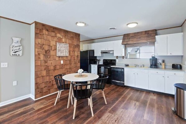 Enjoy meals in the kitchen and dining area, featuring a round table and black chairs.