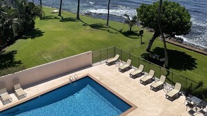 Zona de piscina con sillones de descanso y vista al océano.