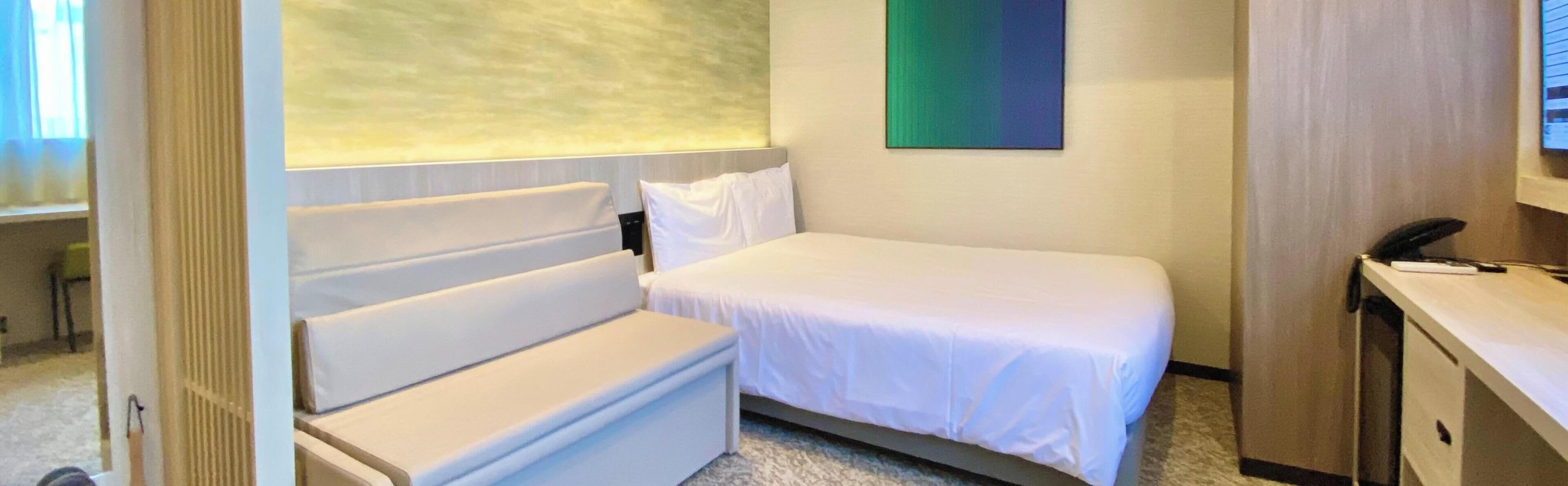A hotel room with a bed, a desk, and a chair.