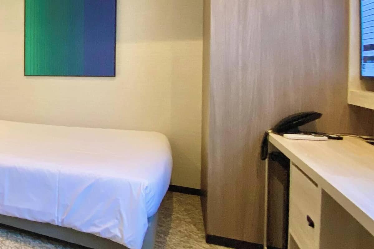 Une chambre d’hôtel avec un lit, un bureau et une chaise.