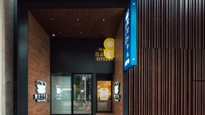 De entree van een hotel met een modern ontwerp, met een houten gevel en glazen deuren.