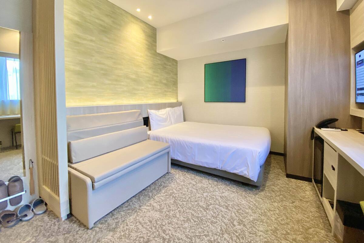 Une chambre d’hôtel comprenant un lit, un coin salon, un bureau et un téléviseur.