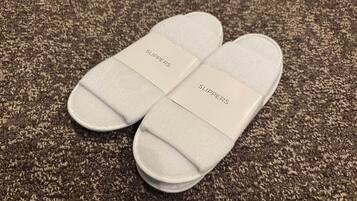 A pair of white slippers with 'SLIPPERS' text on a textured carpet.