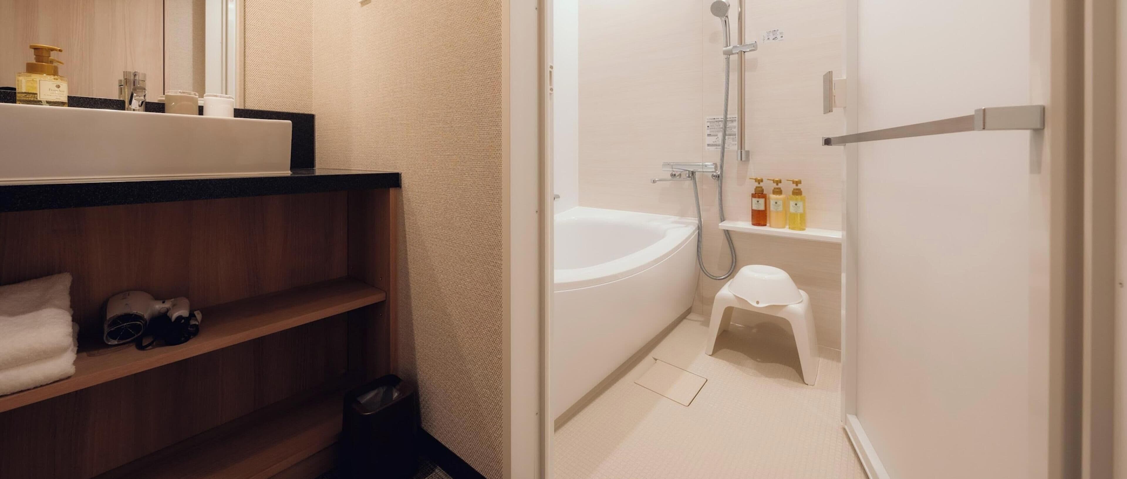 A bathroom with a bathtub, a shower, a small stool, and a shelf with toiletries.