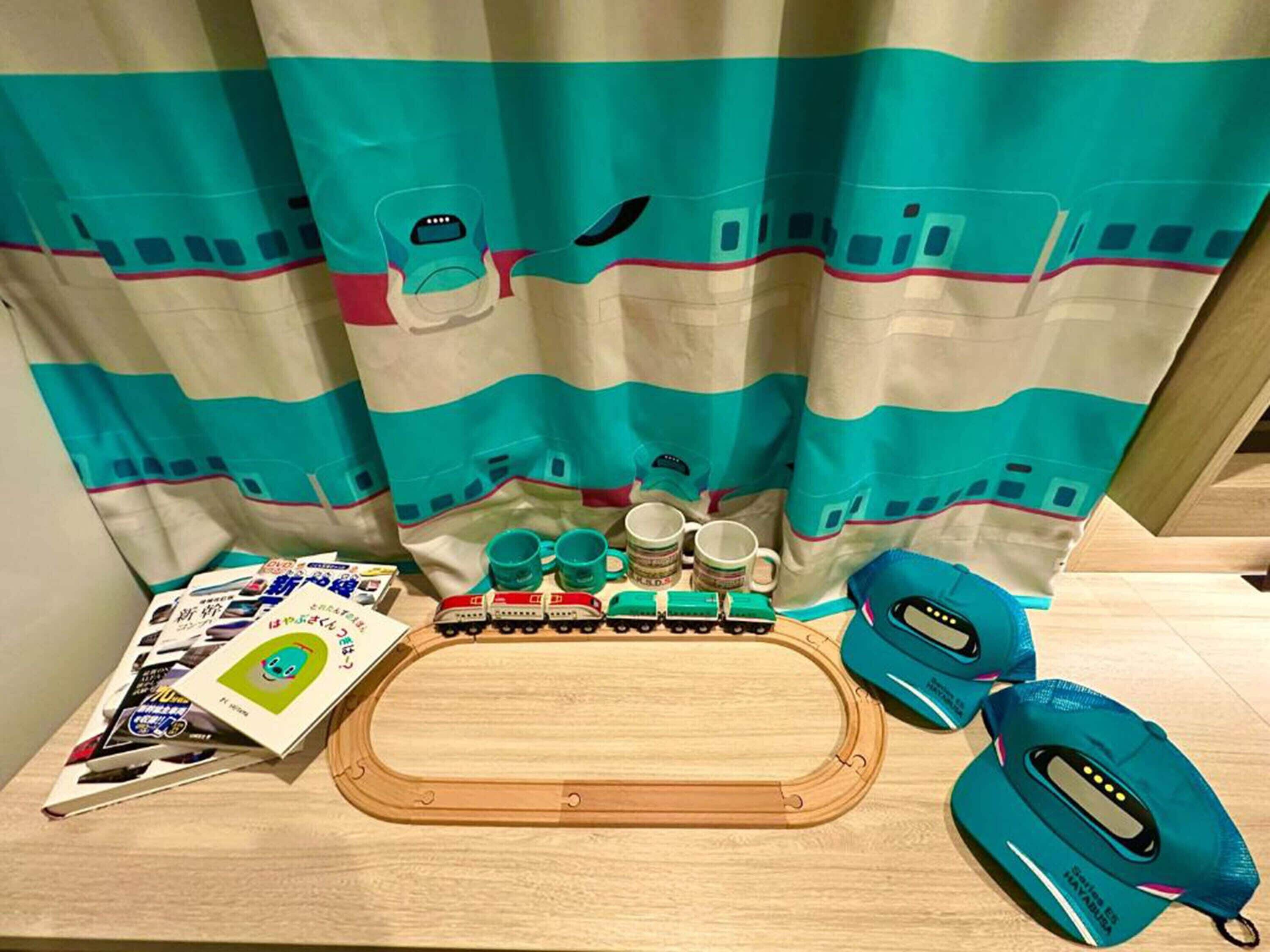 A wooden toy train set, a blue toy car, and a pair of blue headphones on a table.