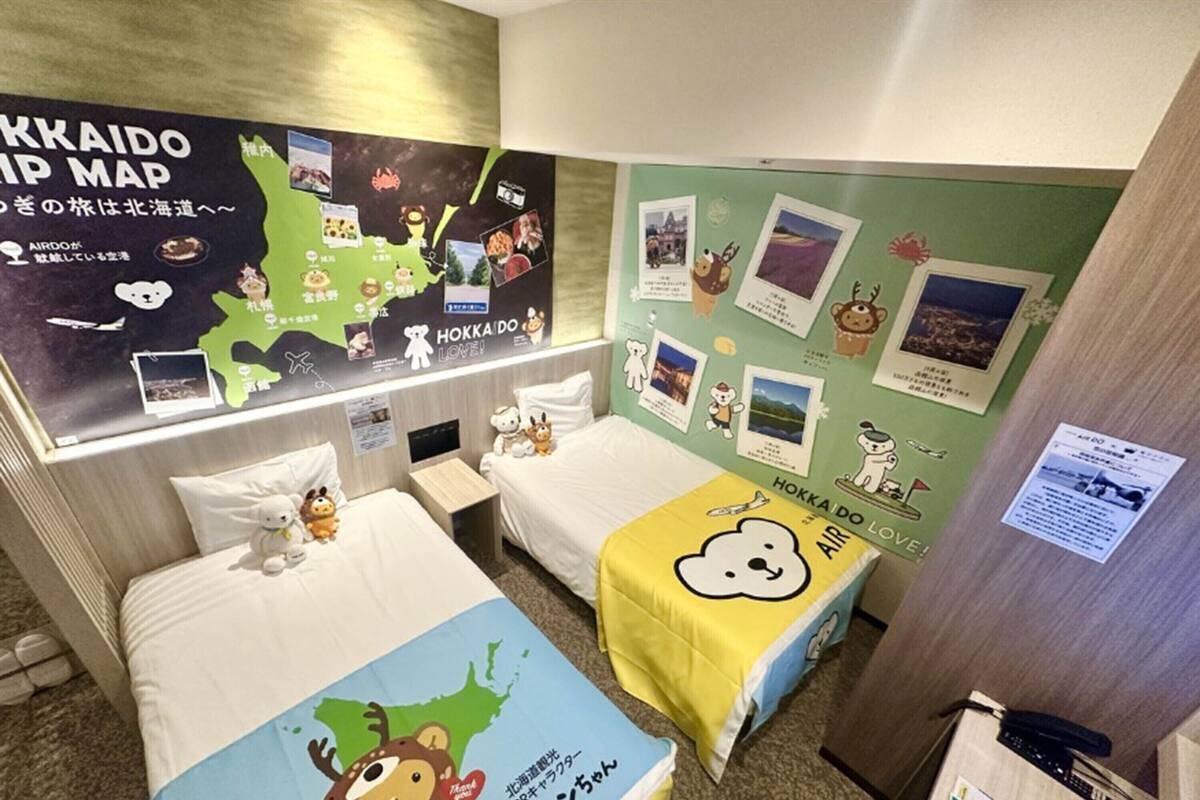 Une chambre d’hôtel avec deux lits, une carte accrochée au mur, ainsi que divers tableaux et autocollants.