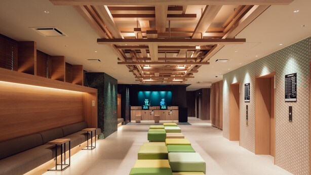Een moderne hotellobby met een lange receptiebalie, een zithoek en een behang met een patroon.