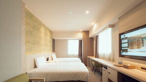 Een hotelkamer met twee bedden, een bureau, een televisie en een groene fauteuil.