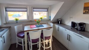 A small kitchenette with a dining table, chairs, and a coffee maker.
