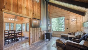 Ein Holzblockbau-Innenraum mit Essbereich, Sofa und Kamin.