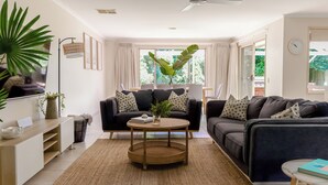 A modern living room with two sofas, a coffee table, and a bookshelf. - Beach Pad - 4pm check out Sundays* (Safety Beach)