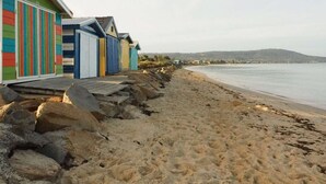 A beach with colorful beach huts and a rocky shoreline. - Beach Pad - 4pm check out Sundays* (Safety Beach)