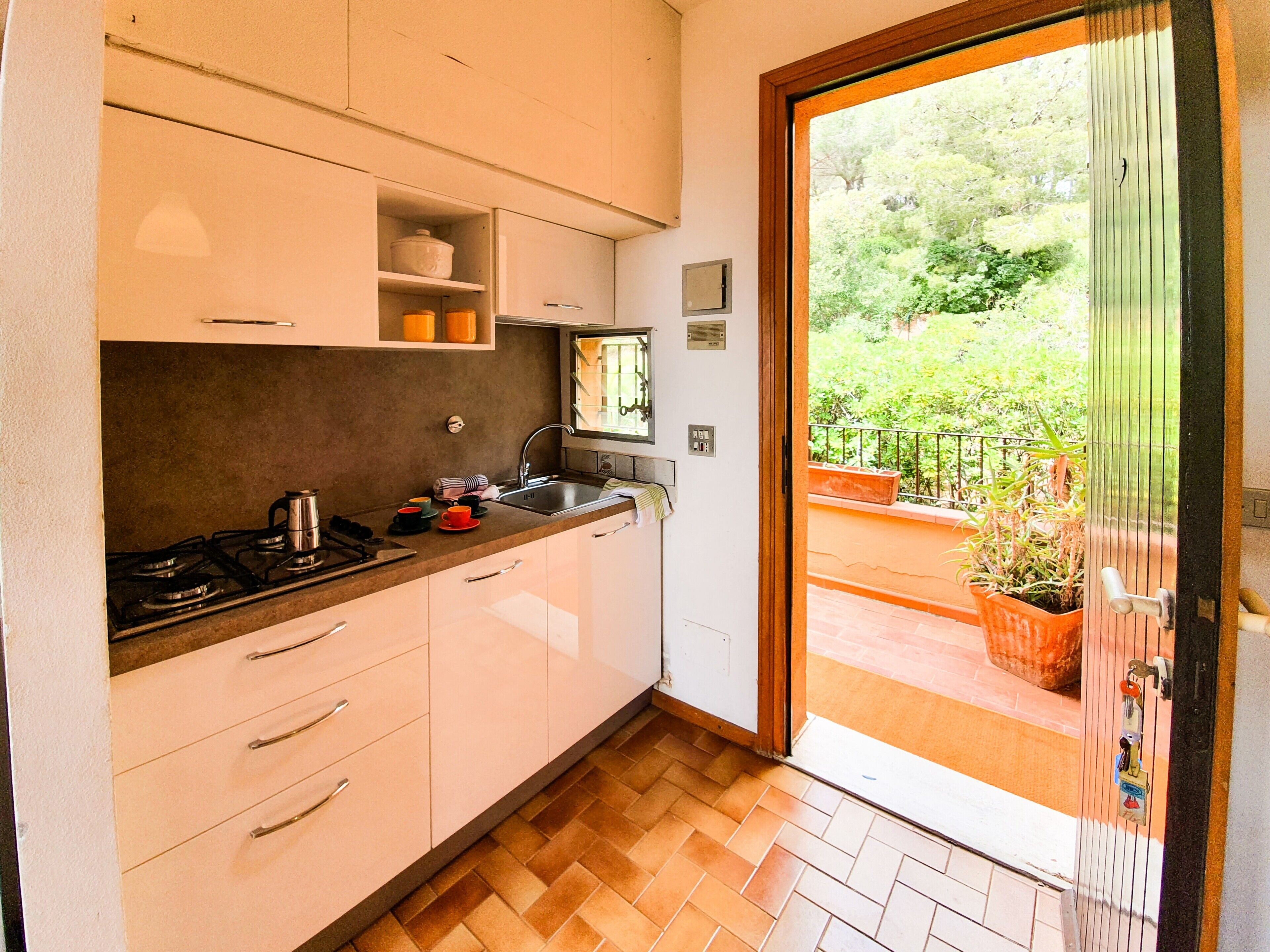 A compact kitchen with a gas stove, sink, and white cabinets.