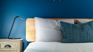A bed with white and teal pillows, a wooden headboard, and a bedside table with a lamp. - Heart of Alberta Arts District, Pet Friendly, Walk to Alberta Park, Food, Art, and Drinks (Portland)
