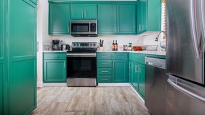 A kitchen with teal cabinets, stainless steel appliances, and a marble countertop. - Heart of Alberta Arts District, Pet Friendly, Walk to Alberta Park, Food, Art, and Drinks (Portland)