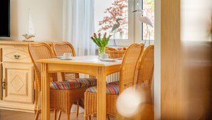 Un coin repas avec une table en bois, des chaises en osier et un vase de fleurs.