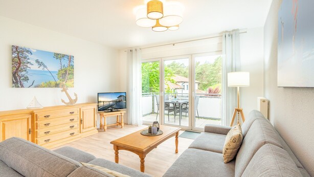 A modern living room with a sofa, coffee table, and TV. There is a wooden cabinet with drawers and a painting on the wall.