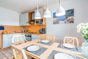 A modern kitchen with white cabinets, a wooden countertop, and a dining area with a wooden table set for two.