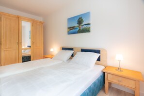 Ein Schlafzimmer mit einem Bett, einem Holzschrank, Nachttischen und einem Wandbild.