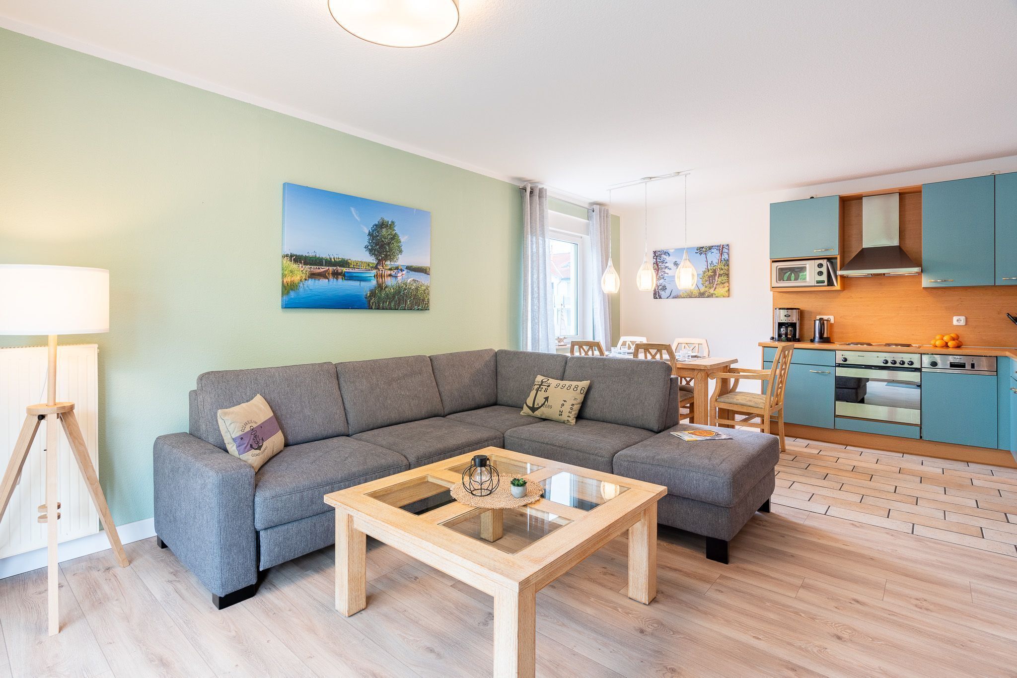 Ein modernes Wohnzimmer mit grauem Sofa, einem Couchtisch mit Glastischplatte und Holzboden.